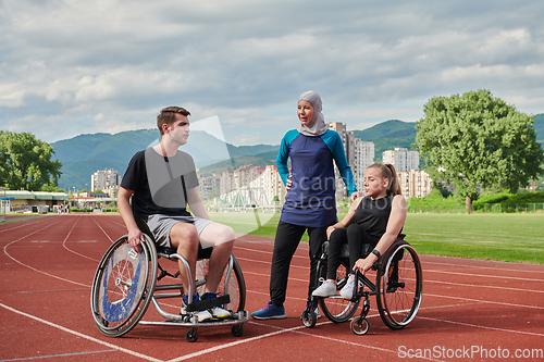 Image of A woman with a disability in a wheelchair talking after training with a woman wearing a hijab and a man in a wheelchair