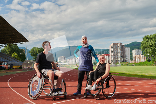 Image of A woman with a disability in a wheelchair talking after training with a woman wearing a hijab and a man in a wheelchair