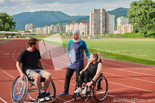 Image of A woman with a disability in a wheelchair talking after training with a woman wearing a hijab and a man in a wheelchair