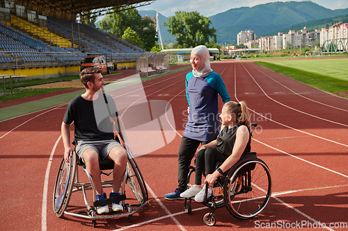 Image of A woman with a disability in a wheelchair talking after training with a woman wearing a hijab and a man in a wheelchair