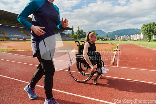 Image of A Muslim woman in a burqa running together with a woman in a wheelchair on the marathon course, preparing for future competitions.