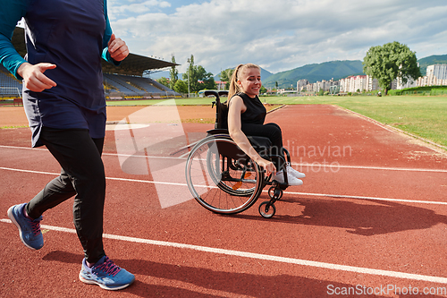 Image of A Muslim woman in a burqa running together with a woman in a wheelchair on the marathon course, preparing for future competitions.