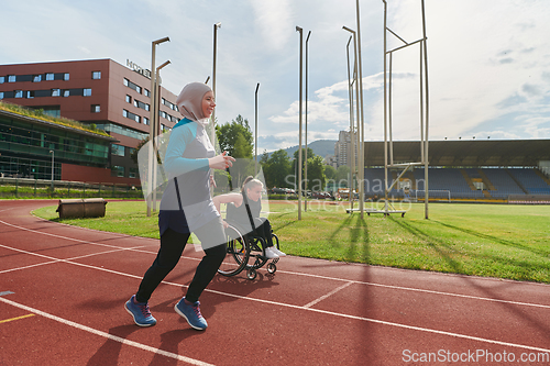 Image of A Muslim woman in a burqa running together with a woman in a wheelchair on the marathon course, preparing for future competitions.