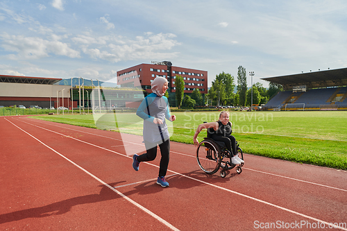 Image of A Muslim woman in a burqa running together with a woman in a wheelchair on the marathon course, preparing for future competitions.