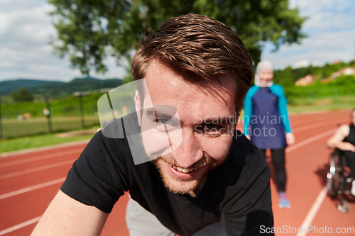 Image of A portrait of a man with a Muslim woman and a woman in a wheelchair running on a marathon track in the background