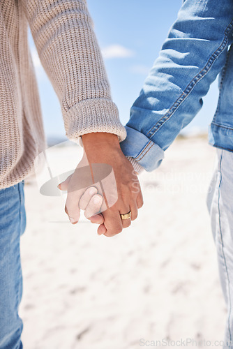 Image of Beach, closeup and couple holding hands for love, commitment and marriage in nature. Travel, bonding and man and woman together by ocean for care, trust and affection on holiday, vacation and weekend