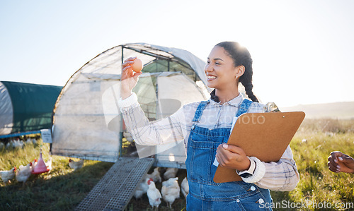 Image of Agriculture, farm and a woman with an egg for inspection and a clipboard for quality control. Farming, sustainability and a poultry farmer person with organic produce outdoor for growth or production