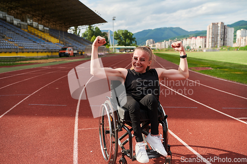 Image of A woman with disability in a wheelchair showing dedication and strength by showing her muscles