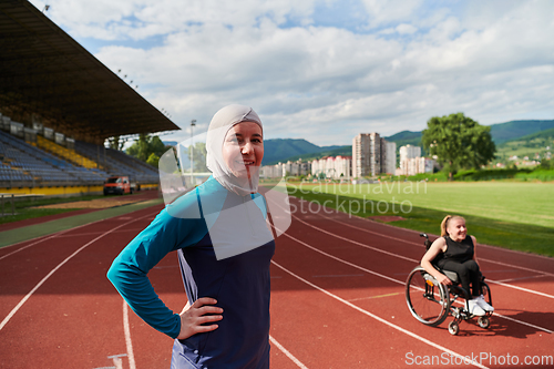 Image of A Muslim woman wearing a burqa resting with a woman with disability after a hard training session on the marathon course