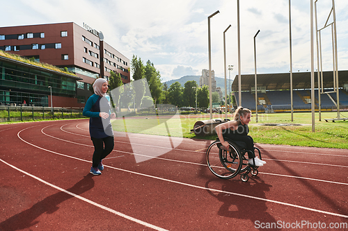 Image of A Muslim woman in a burqa running together with a woman in a wheelchair on the marathon course, preparing for future competitions.