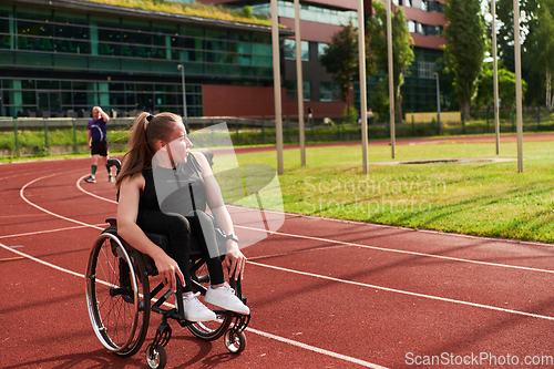 Image of A Muslim woman in a burqa running together with a woman in a wheelchair on the marathon course, preparing for future competitions.