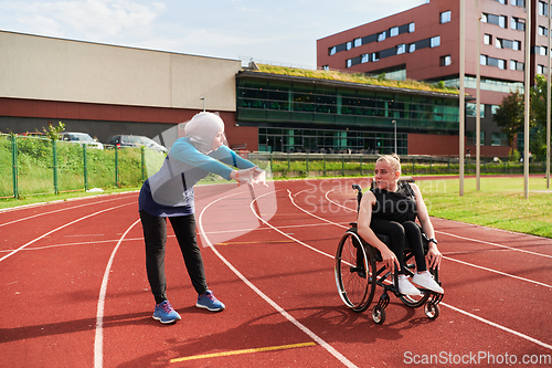 Image of A Muslim woman in a burqa running together with a woman in a wheelchair on the marathon course, preparing for future competitions.