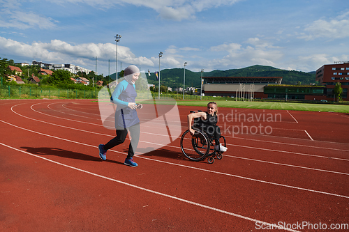 Image of A Muslim woman in a burqa running together with a woman in a wheelchair on the marathon course, preparing for future competitions.