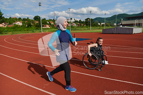 Image of A Muslim woman in a burqa running together with a woman in a wheelchair on the marathon course, preparing for future competitions.