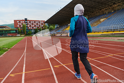 Image of A muslim woman in a burqa sports muslim clothes running on a marathon course and preparing for upcoming competitions