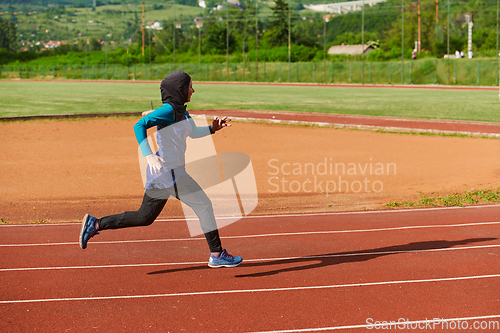 Image of A muslim woman in a burqa sports muslim clothes running on a marathon course and preparing for upcoming competitions