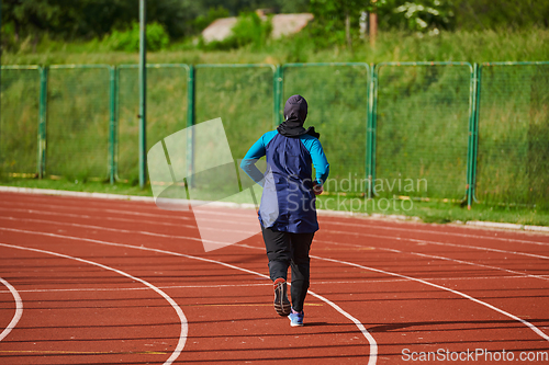 Image of A muslim woman in a burqa sports muslim clothes running on a marathon course and preparing for upcoming competitions