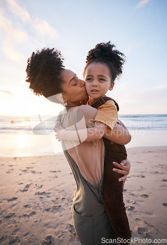 Image of Beach, sunset and mother kissing her child on a family vacation, holiday or travel adventure. Love, care and mom holding, hugging and bonding with her girl kid by the ocean on weekend trip in Mexico.