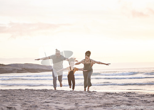 Image of Happy, freedom and a family at the beach during sunset for flying, playing and bonding at the ocean. Smile, carefree and an interracial child, mother and father at the sea for a vacation or summer