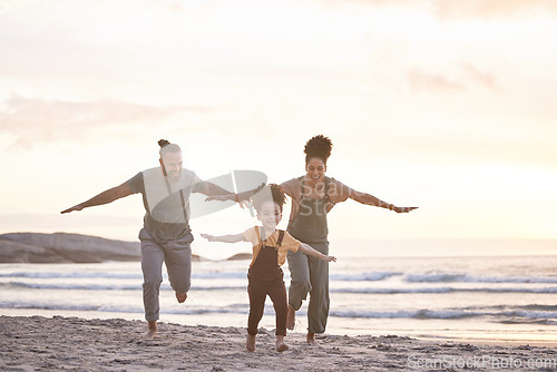 Image of Travel, freedom and a family at the beach during sunset for flying, playing and bonding at the ocean. Smile, holiday and an interracial child, mother and father at the sea for a vacation or summer