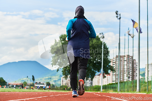 Image of A muslim woman in a burqa sports muslim clothes running on a marathon course and preparing for upcoming competitions