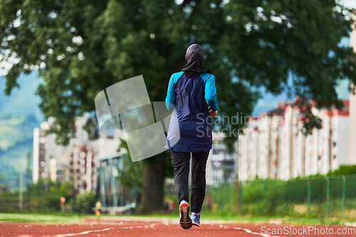 Image of A muslim woman in a burqa sports muslim clothes running on a marathon course and preparing for upcoming competitions