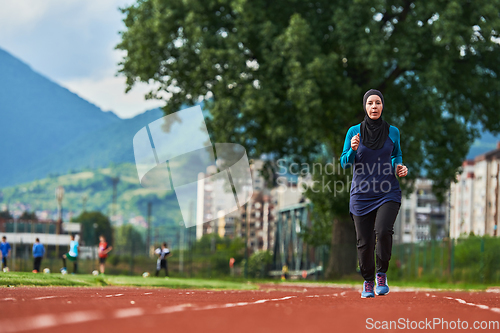 Image of A muslim woman in a burqa sports muslim clothes running on a marathon course and preparing for upcoming competitions