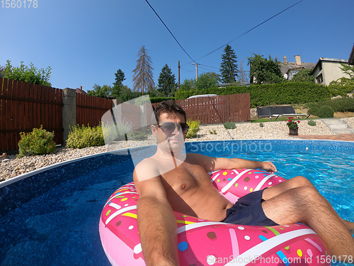 Image of Happy man relax on inflatable ring. Holiday 2020