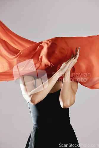 Image of Fashion, textile and wind with a model in studio on a gray background for runway or magazine cover style. Abstract, fabric and hidden face with a trendy young woman posing in a material outfit