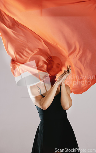 Image of Fashion, fabric and breeze with a model in studio on a gray background for runway or magazine cover style. Abstract, textile wind and hidden face with a trendy young woman posing in a material outfit