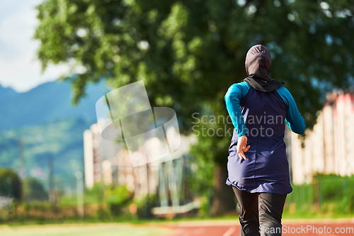 Image of A muslim woman in a burqa sports muslim clothes running on a marathon course and preparing for upcoming competitions