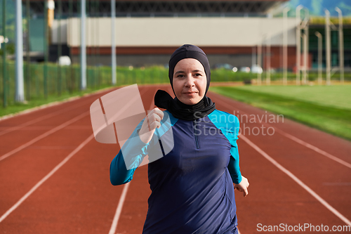 Image of A muslim woman in a burqa sports muslim clothes running on a marathon course and preparing for upcoming competitions