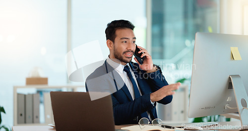 Image of Happy business man talking on his phone while working on a computer and smiling alone at work. Young corporate professional having a discussion and explaining project details to a colleague or client