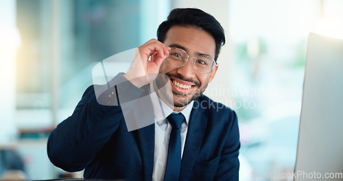 Image of Happy young business man looking ready for the day while working on a computer and smiling alone at work. Portrait of one corporate professional looking confident and successful in the office