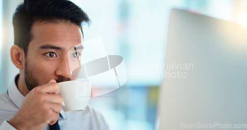 Image of Focused lawyer sipping a cappuccino while working on a case for his upcoming legal trial. Closeup of the face and head of a young male advocate researching the law on his computer while preparing