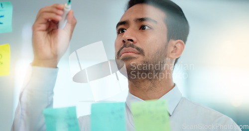 Image of Project manager planning a strategy while writing notes on a glass wall in an office. Businessman brainstorming and thinking of ideas for his presentation. Serious male entrepreneur being innovative