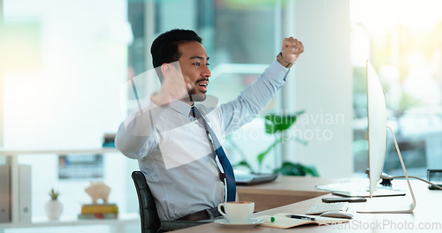 Image of Excited business man cheering at his desk. Successful male banker or happy financial advisor celebrating his trading victory in a modern office. Young guy reading good news on his computer at work.