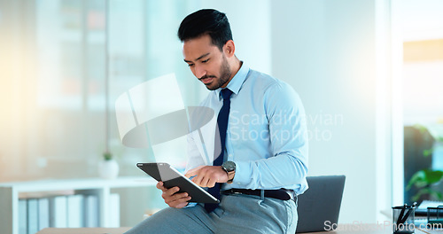 Image of Successful young business man laughing while browsing on a tablet in the office. Portrait of a confident male corporate professional feeling positive after completing a deal or finishing a task