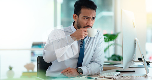Image of Exhausted businessman typing on a computer working and sipping coffee in a corporate office. A male employee sitting at a desk feeling sleepy and yawning tired from overworked job and drinking coffee
