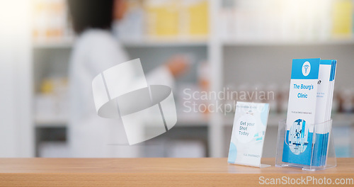 Image of Focus on an information pamphlet on a counter at a pharmacy, advertising treatment and health care with a pharmacist packing rows medication on a shelf in a modern drugstore against blur background