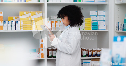 Image of Young and focused pharmacist use her tablet to do stock taking in a modern pharmacy drugstore. Multiethnic female health professional worker or medication expert in a chemist using a digital gadget