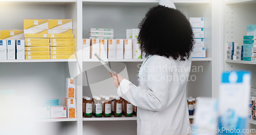 Image of Young and focused pharmacist use her tablet to do stock taking in a modern pharmacy drugstore. Multiethnic female health professional worker or medication expert in a chemist using a digital gadget