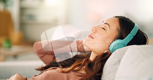 Image of Woman headphones, listening to relax music, podcast and smile with a calm, zen and peaceful day at home. Happy Asian female and relaxed woman sitting on a living room sofa and meditation with audio