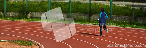 Image of A muslim woman in a burqa sports muslim clothes running on a marathon course and preparing for upcoming competitions