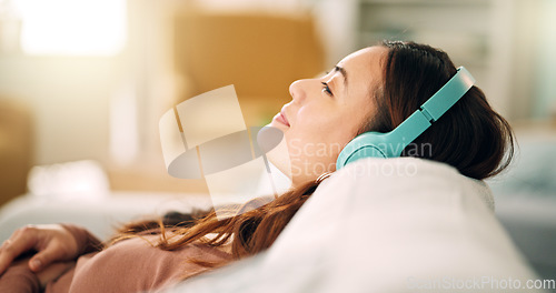 Image of Relax, headphones and happy woman listening to music, radio or podcast while resting on sofa. Happiness, smile and calm girl from singapore sitting on the couch in living room at home with technology