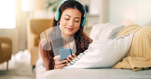 Image of Relax, music and phone with woman in living room and headphones listening to radio, podcast or podcast. Happy, freedom and internet with girl on sofa, streaming for audio, social media or online