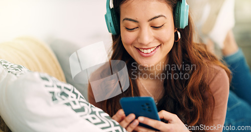 Image of Girl, phone and music on sofa to relax with headphones with smile, typing and happy on social media. Woman, smartphone and streaming song on internet while reading communication, blog post or email