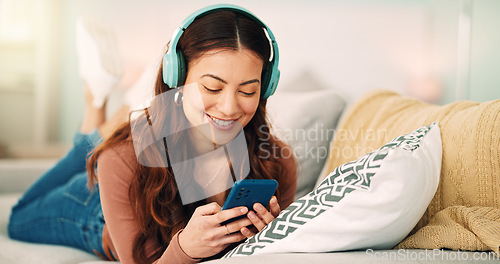 Image of Girl, phone and music on sofa to relax with headphones with smile, typing and happy on social media. Woman, smartphone and streaming song on internet while reading communication, blog post or email