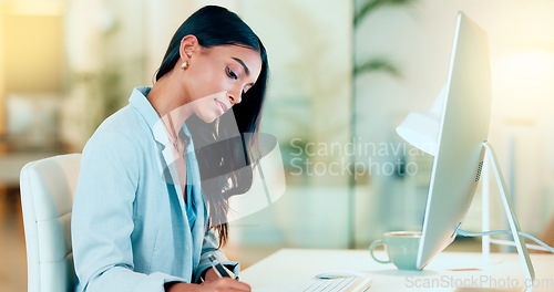 Image of Businesswoman typing out financial reports while working on a computer in her office. Female accountant managing finances and doing bookkeeping using software to compile data and writing notes