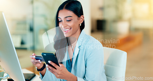 Image of Happy woman making online payment with phone and bank card for typing credit details into online banking app. Young business woman enjoying virtual shopping or wireless purchase while sitting inside